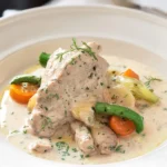 Blanquette de veau à l'ancienne servie dans une assiette avec légumes et sauce crémeuse