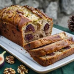 Un cake salé aux figues, noix et roquefort coupé en tranches sur une planche dans une cuisine maison.