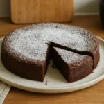 Photo d’un gâteau au chocolat sans farine, fait maison, fondant et moelleux, présenté dans une cuisine familiale avec une touche de sucre glace.