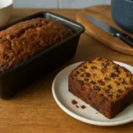 Photo d'un gateau anglais traditionnel aux fruits, fait maison, moelleux et doré, avec fruits confits et raisins secs, présenté sur une table de cuisine dans une ambiance chaleureuse.