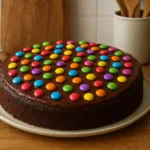 Image d’un gâteau aux Smarties maison, moelleux et coloré, décoré de bonbons Smarties sur un glaçage au chocolat, parfait pour un anniversaire d’enfant ou un goûter festif.