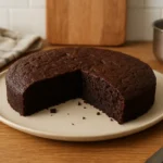 Photo d’un gâteau végétalien facile et moelleux au chocolat, fait maison, sans œufs ni lait, posé sur un plan de travail de cuisine avec des ustensiles autour – une recette vegan simple, gourmande et 100 % végétale.