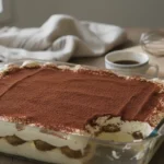 Tiramisu au café maison saupoudré de cacao dans un plat en verre